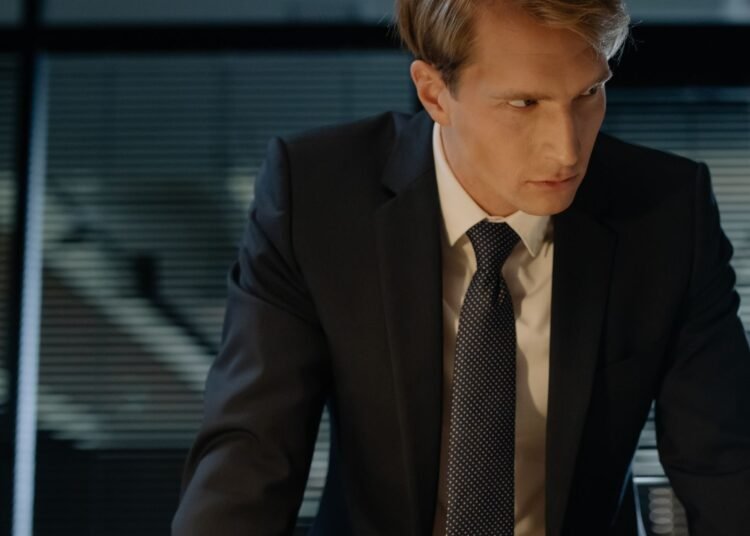A professional man in a suit leaning over a desk, Positive Phil
