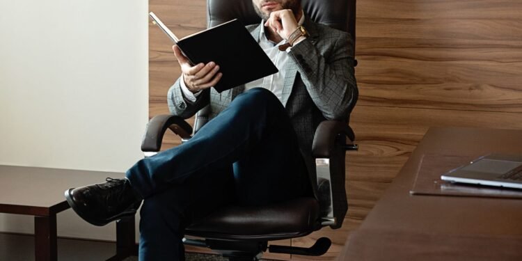 A man in a suit reading in a stylish office, Positive Phil