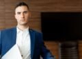 A confident young businessman holding a laptop, Positive Phil