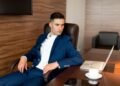A businessman in a blue suit at his desk, Positive Phil