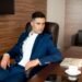 A businessman in a blue suit at his desk, Positive Phil