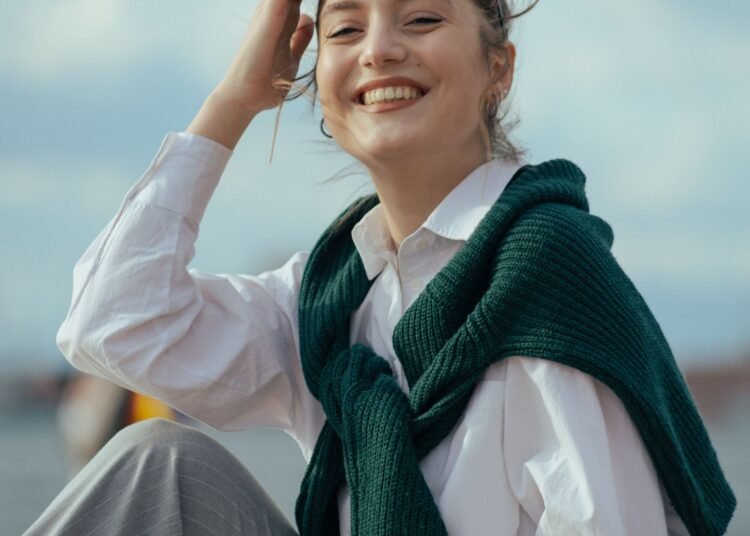 A woman in a sweater smiling outdoors, Positive Phil