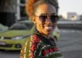 A woman in a colorful sweater smiling in the city, Positive Phil