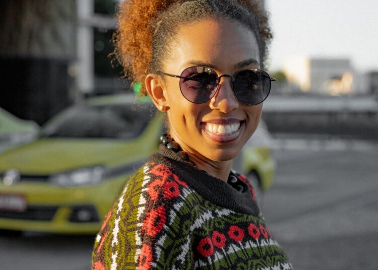 A woman in a colorful sweater smiling in the city, Positive Phil