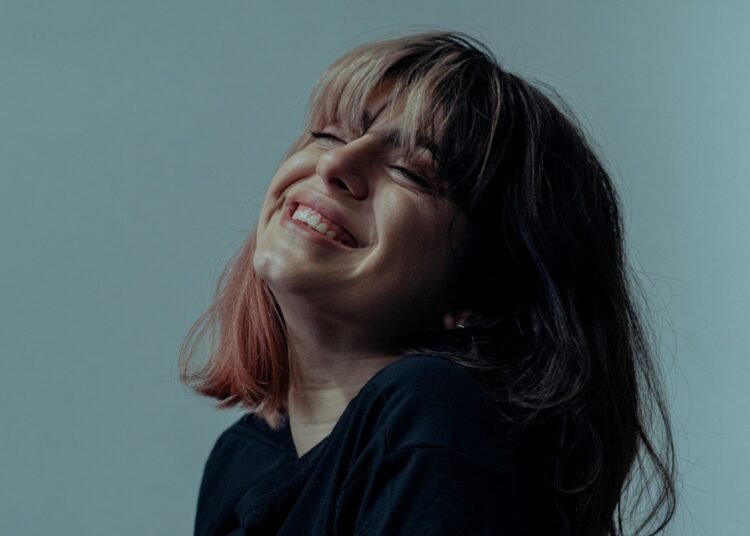 A cheerful woman smiling indoors, Positive Phil
