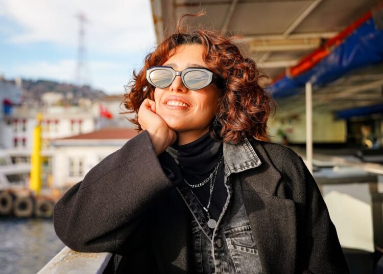 A woman in sunglasses enjoying a sunny ferry ride, Positive Phil