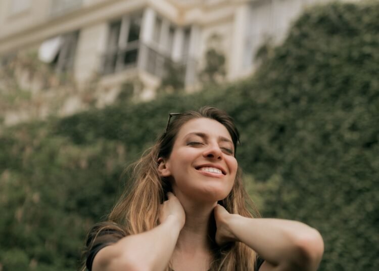 A smiling woman enjoying a calm moment outdoors, Positive Phil