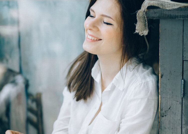 A woman in a white shirt smiling with closed eyes, Positive Phil