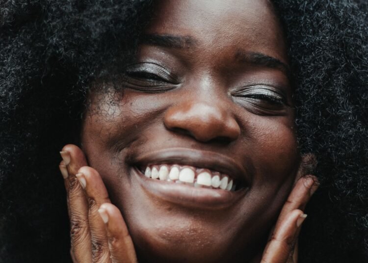 A woman with curly hair smiling warmly, Positive Phil