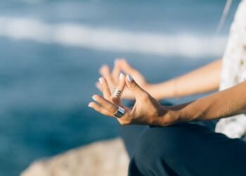 Hands resting in a meditation pose by the ocean