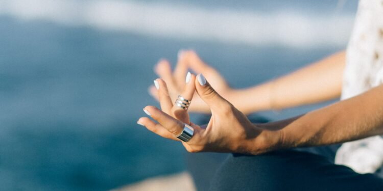 Hands resting in a meditation pose by the ocean