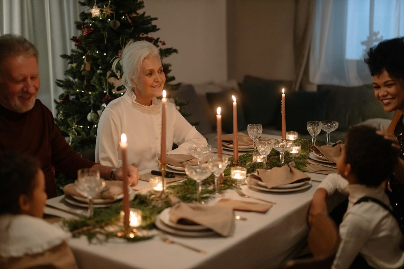 A grandmother smiling at a dinner table with her family