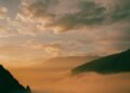 Golden sunrise glowing through low clouds over misty hills