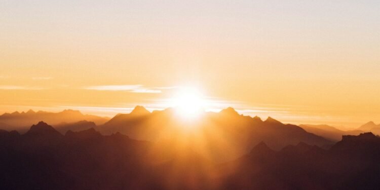 Sun breaking over a dark mountain ridge