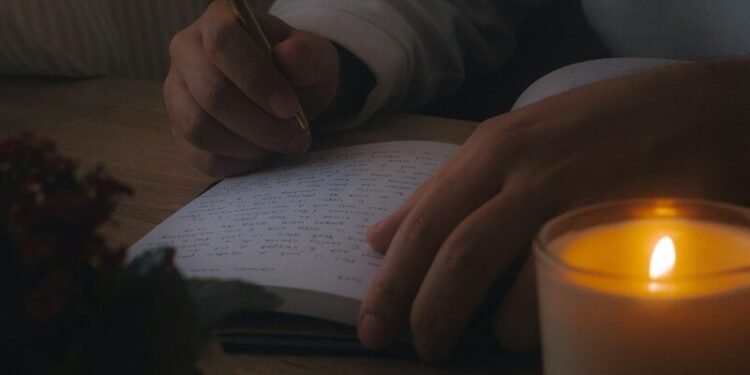 Person writing in a journal by candlelight