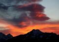 a red and orange sky with a mountain in the background