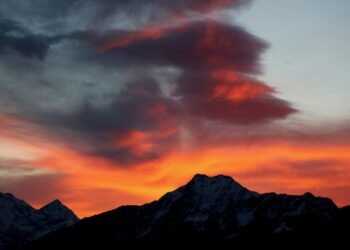 a red and orange sky with a mountain in the background